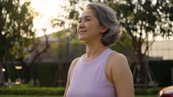 A woman standing peacefully outdoors at golden hour