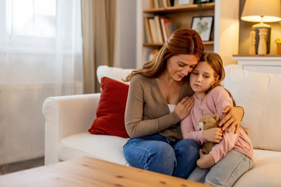A mother holding her daughter on a couch